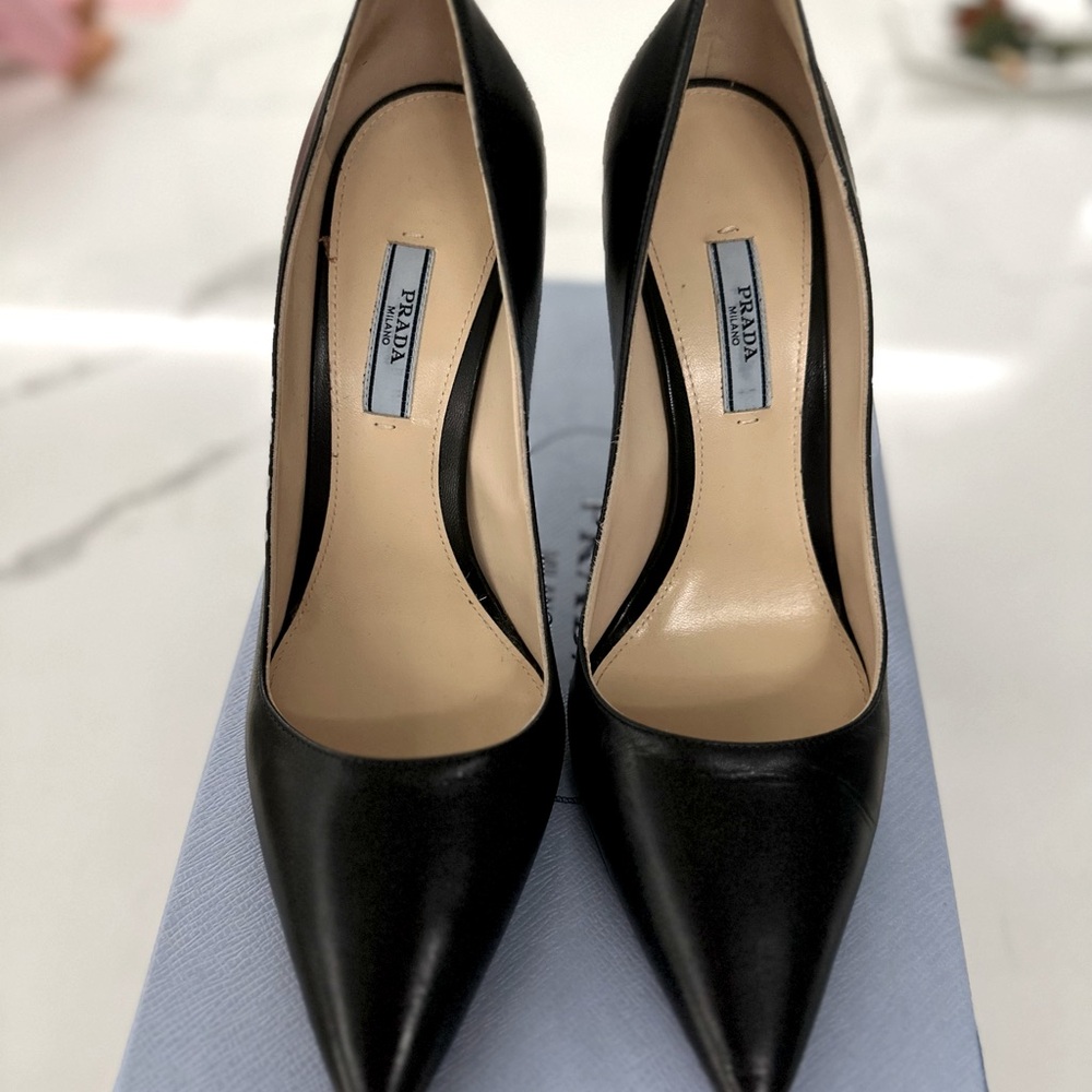Prada Pumps decorated with Prada's iconic metal logo express timeless elegance.